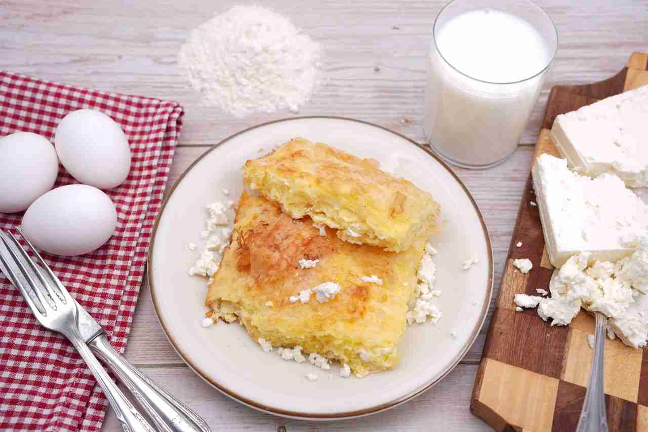 gallery-5 Scrumptious homemade pastry served with cottage cheese, eggs, and milk on a wooden table.
